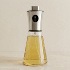 Clear glass bottle with metal cap containing a yellow liquid on a beige background