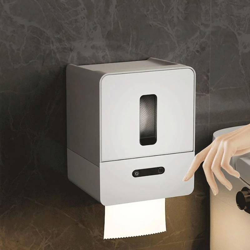 Wall-mounted paper towel dispenser with a hand reaching for a roll of paper towels.