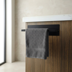 Gray towel hanging on a black towel rack attached to a wooden cabinet with a white countertop.
