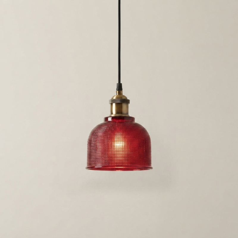 A vintage-style pendant light with a textured red glass shade, brass metal cap, and a black hanging cord against a plain light gray background.