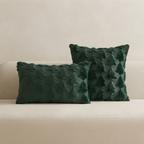 Two dark green textured throw pillows with a raised tree pattern, displayed on a light beige sofa against a neutral beige wall.