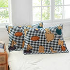 Two decorative rectangular throw pillows with a black and white houndstooth pattern and large applique letters spelling 'PARLAI', styled on a white bed in a bright bedroom.