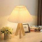 Table lamp with pleated shade on a surface next to books and a photo frame.