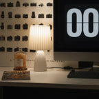 Desk setup with a lamp, computer monitor displaying '00', and a bottle on a wall with camera designs.