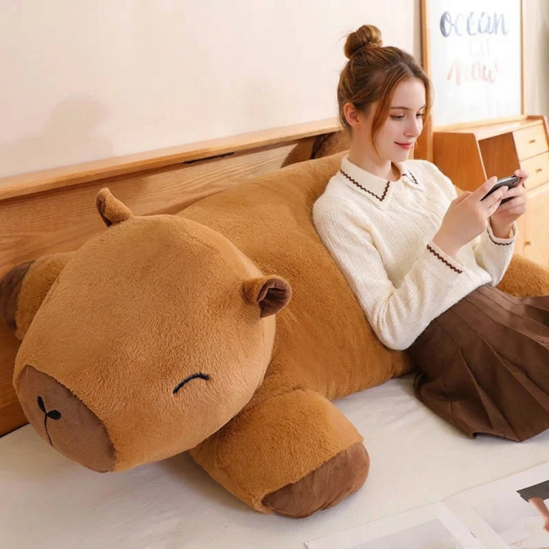Woman sitting on a bed with a large brown hippo-shaped pillow