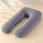 A U-shaped travel neck pillow in a solid medium gray color, resting on a light beige wooden surface.