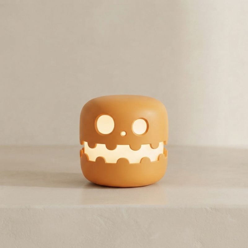 A small, cute, cube-shaped orange lamp shaped like a smiling monster or sandwich, sitting on a light beige surface against a neutral beige background.