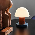 Small table lamp with a wooden base on a dark surface against a gray wall
