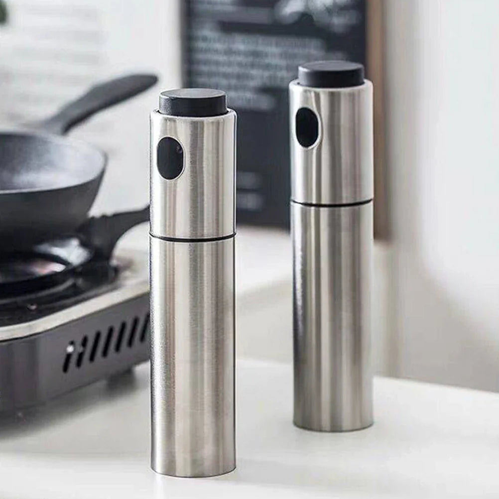 Two stainless steel pepper mills on a kitchen counter with a blurred background.