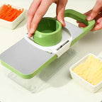 Green and white kitchen slicer with carrots and cheese on a light background