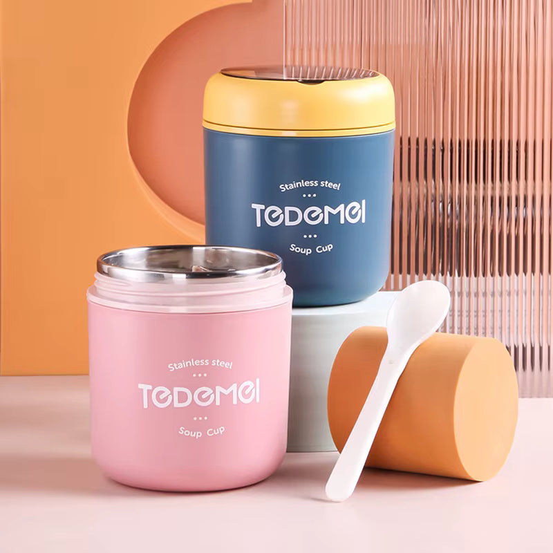 Two stainless steel soup cups, one pink and one blue, with a white spoon on a peach background.