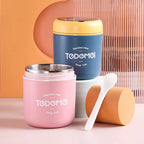 Two stainless steel soup cups, one pink and one blue, with a white spoon on a peach background.