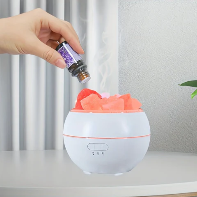 Hand adding a diffuser bottle to a white diffuser with colorful flowers on a neutral background