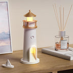 Lighthouse-shaped night light on a wooden surface with a diffuser bottle and book in the background.