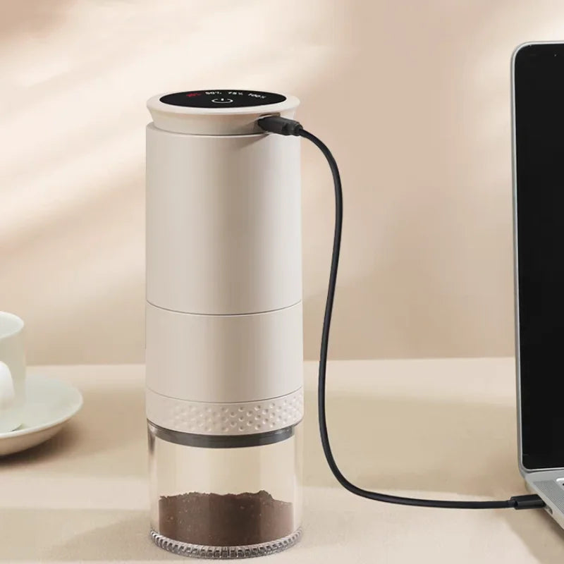 White coffee grinder on a table with a laptop in the background