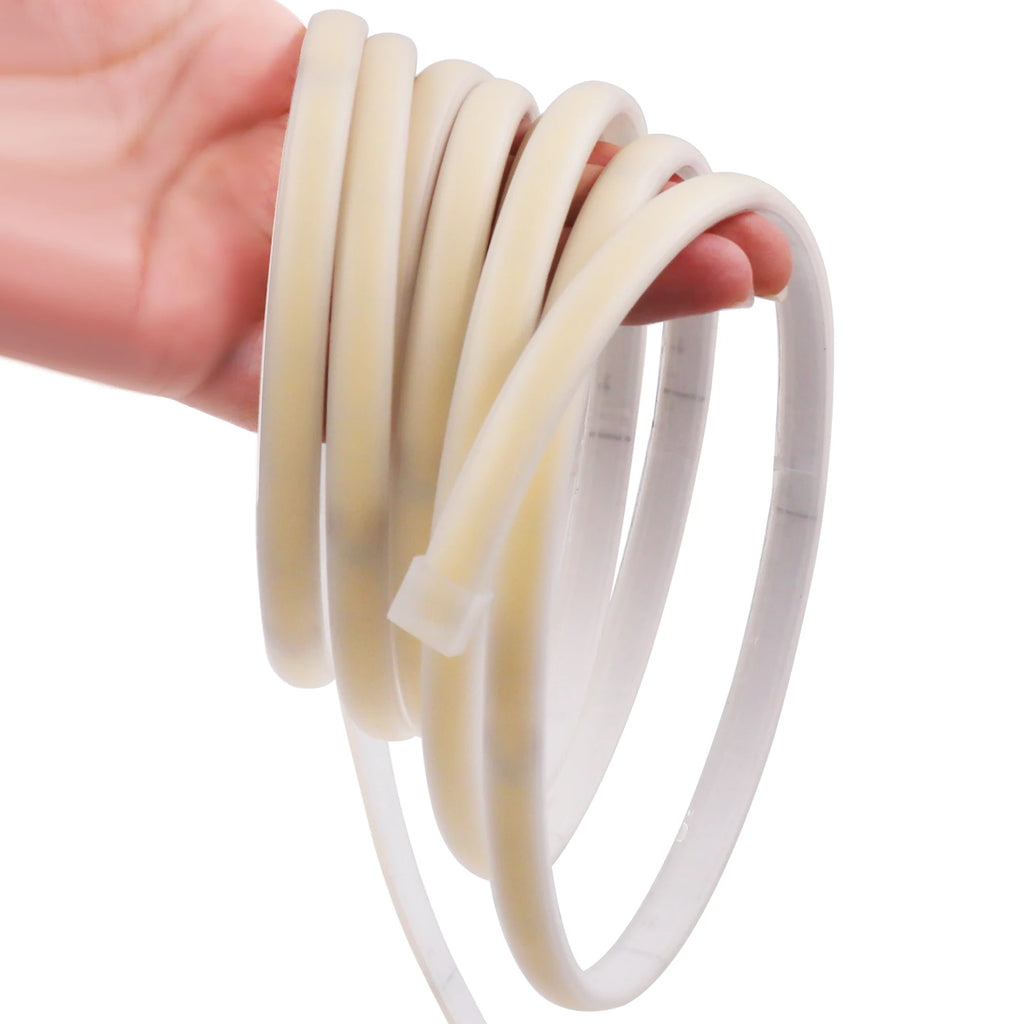 Hand holding a roll of white silicone tubing against a white background