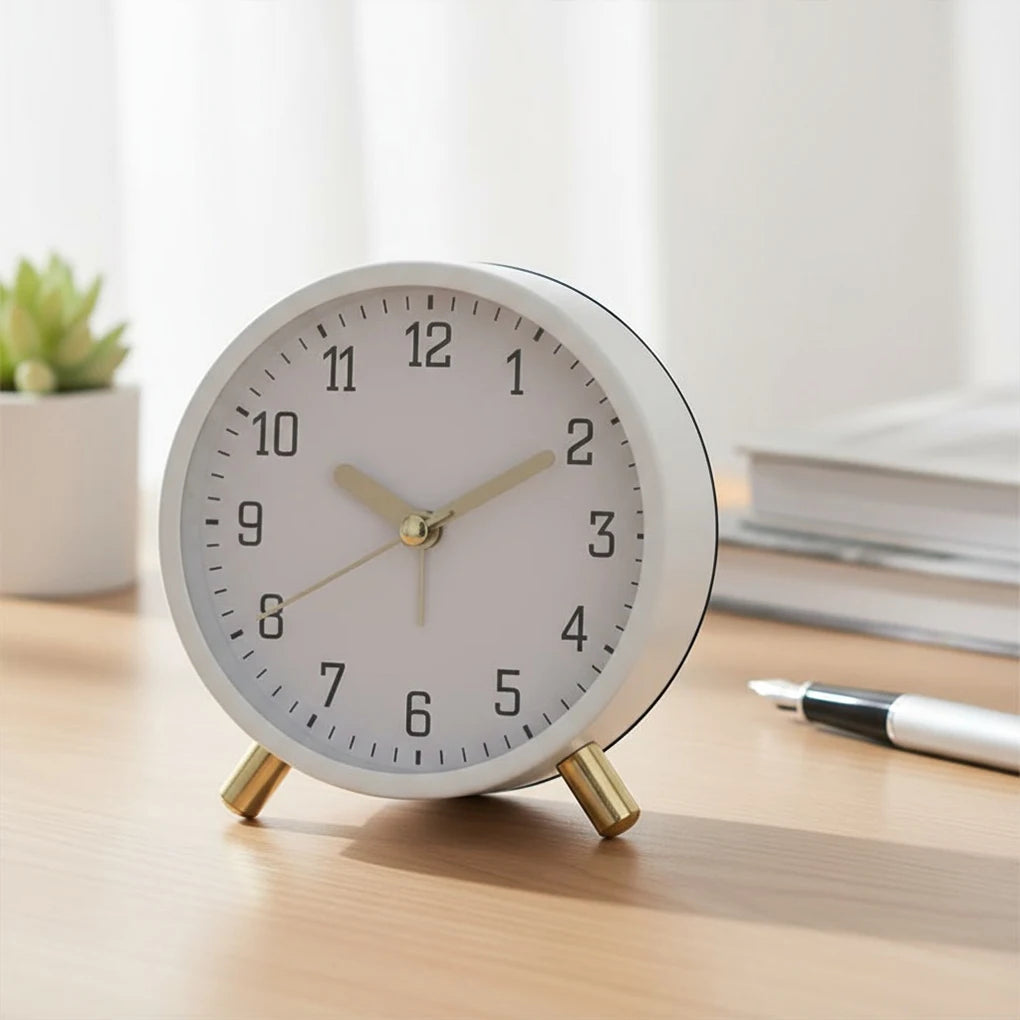 White alarm clock with gold accents on a wooden surface