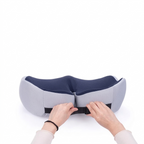 Person adjusting a gray and blue travel pillow on a white background