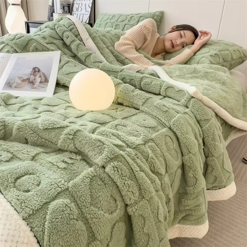 Woman lying on a bed with a green textured blanket, surrounded by decor items.