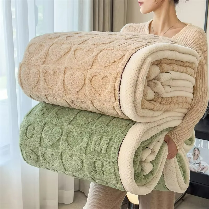 Person holding two folded textured blankets, one beige and one green, against a neutral background.