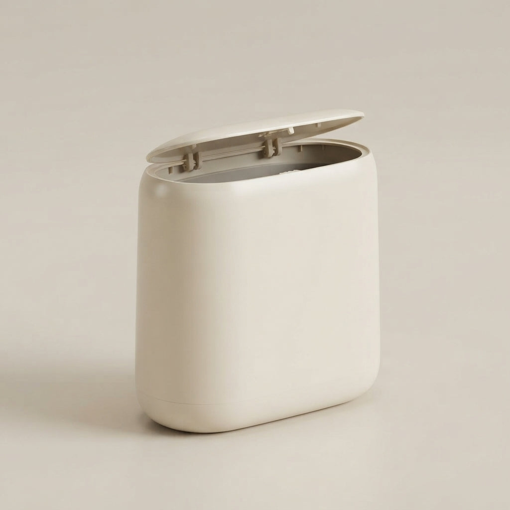 A minimalist, rounded rectangular trash can with a hinged lid in a warm off-white color, set against a matching light beige background.