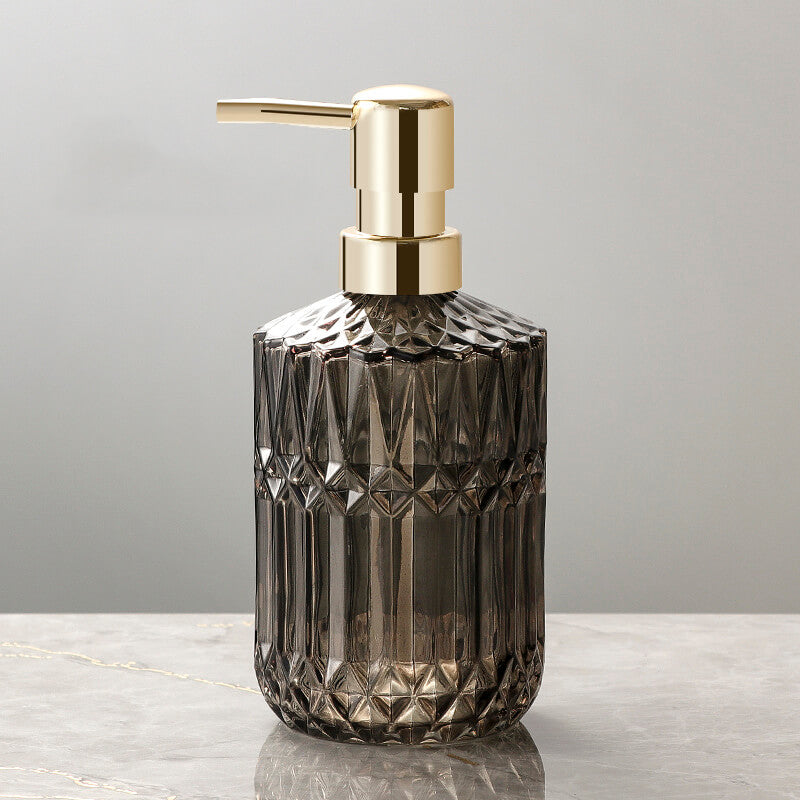 Decorative soap dispenser with gold pump on a gray background