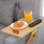 Wooden tray on a couch with croissants, orange juice, and remote control.