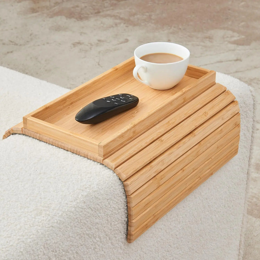 Wooden tray on a bed with a cup of coffee and remote control