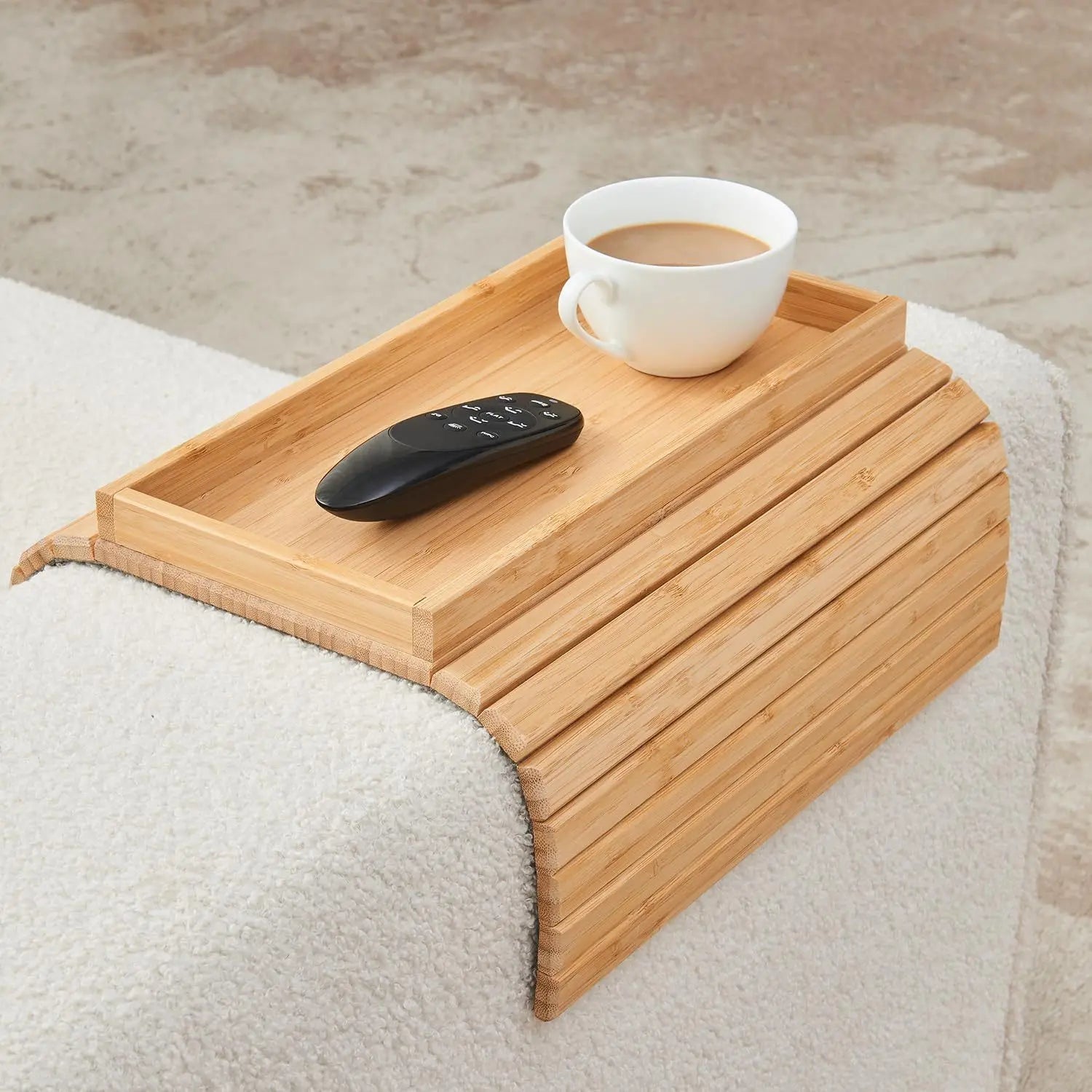 Wooden tray on a bed with a cup of coffee and remote control