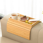 Wooden tray on a couch with a cup of tea, cake, and snacks.
