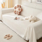 White sofa with decorative pillows and a blanket in a cozy living room setting.