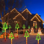 Outdoor Christmas yard lights displayed in front of a house at dusk, including glowing green tree lights, red-and-white striped pole lights, snowman figures, and warm white string lights on the house and trees.