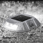 Solar-powered outdoor light fixture on a wet pavement