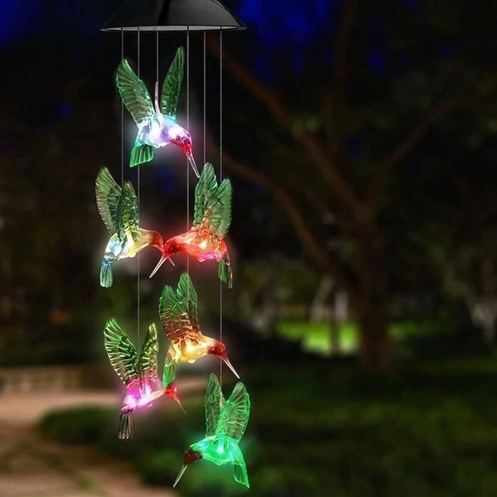 Colorful hummingbird-shaped wind chime with solar lights against a dark background