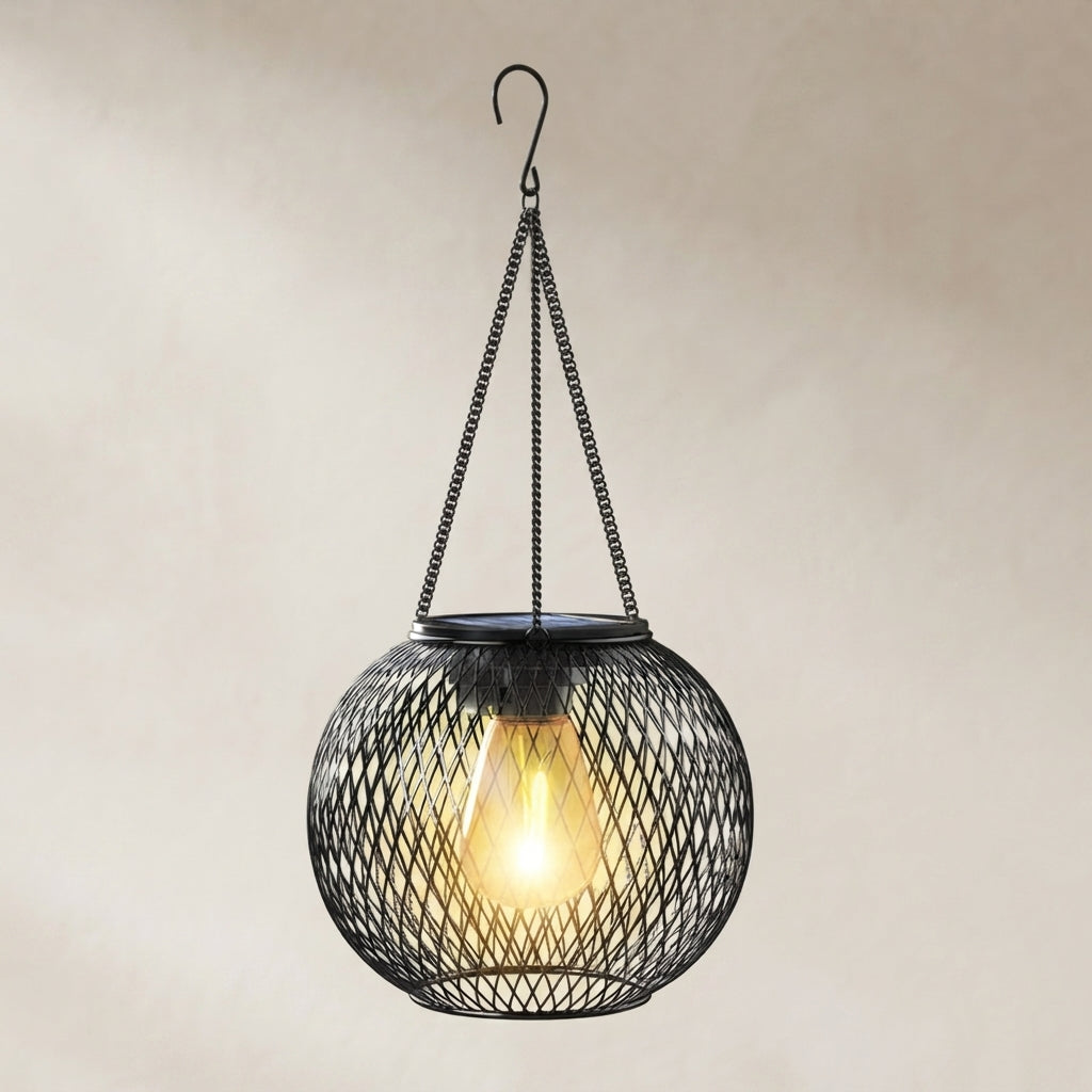 A spherical black metal mesh pendant light with a glowing warm Edison bulb inside, suspended by chains from a hook against a neutral beige background.