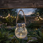 Hanging glass lantern with string lights in a garden setting