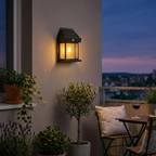 Solar wall light on a balcony with plants and a table at dusk.