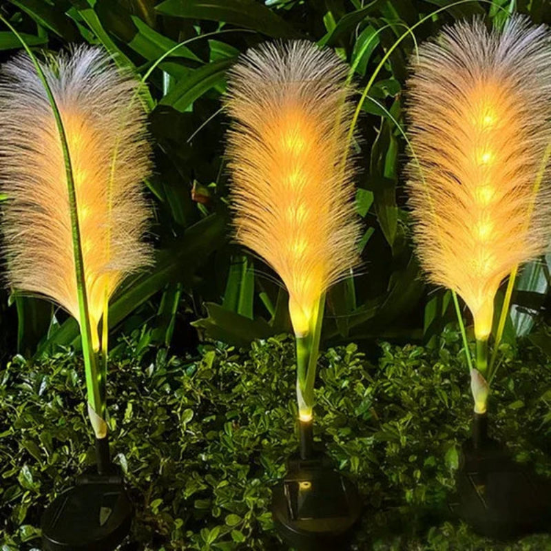 Three illuminated feather-like solar lights on a green leafy background