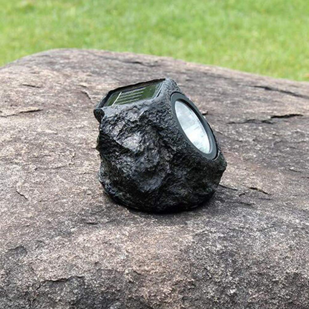 Solar-powered rock light on a stone surface with grass in the background