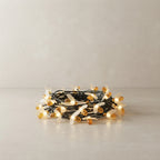 Coiled string lights with warm white bulbs and amber-colored glass, resting on a light gray surface against a neutral beige wall.