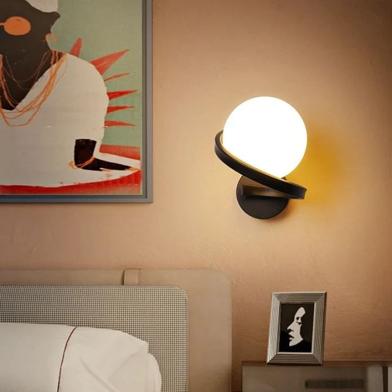 Wall-mounted lamp with a round glass shade in a bedroom setting.