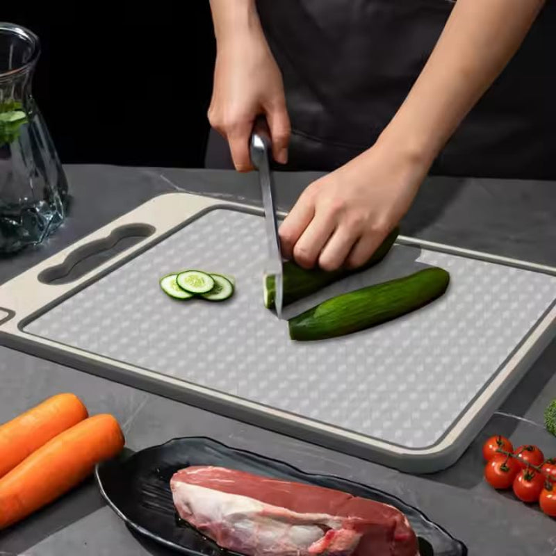 Person cutting vegetables on a cutting board with carrots, tomatoes, and meat in the foreground.