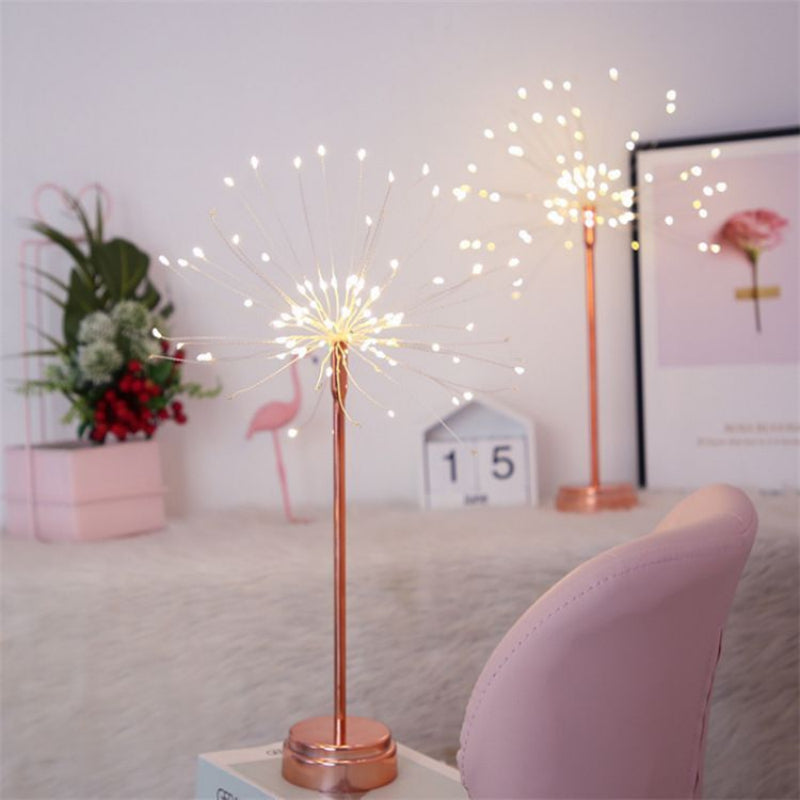 Decorative sparklers on a table with a pink chair and plant in the background