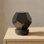 Geometric black sculpture on a wooden surface with a neutral background