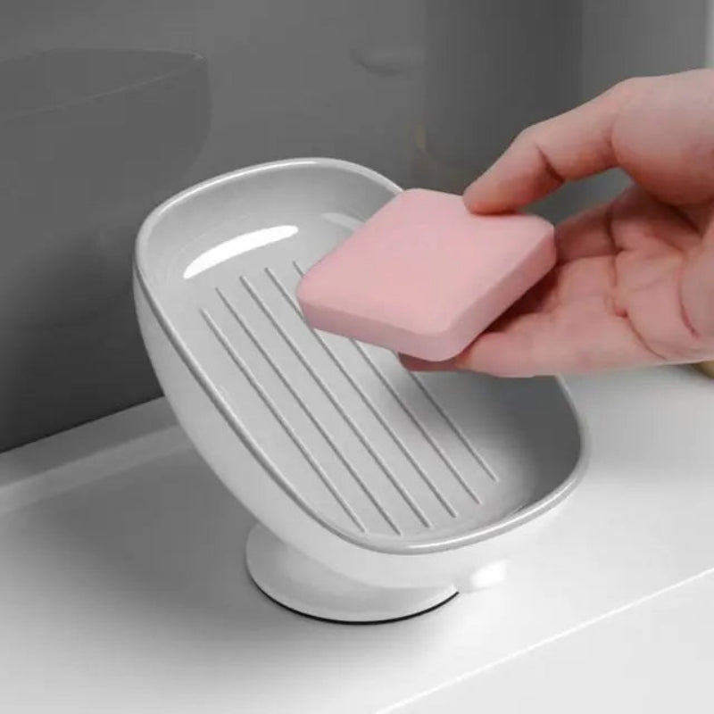 Person placing a pink soap bar into a white soap dish on a bathroom counter.