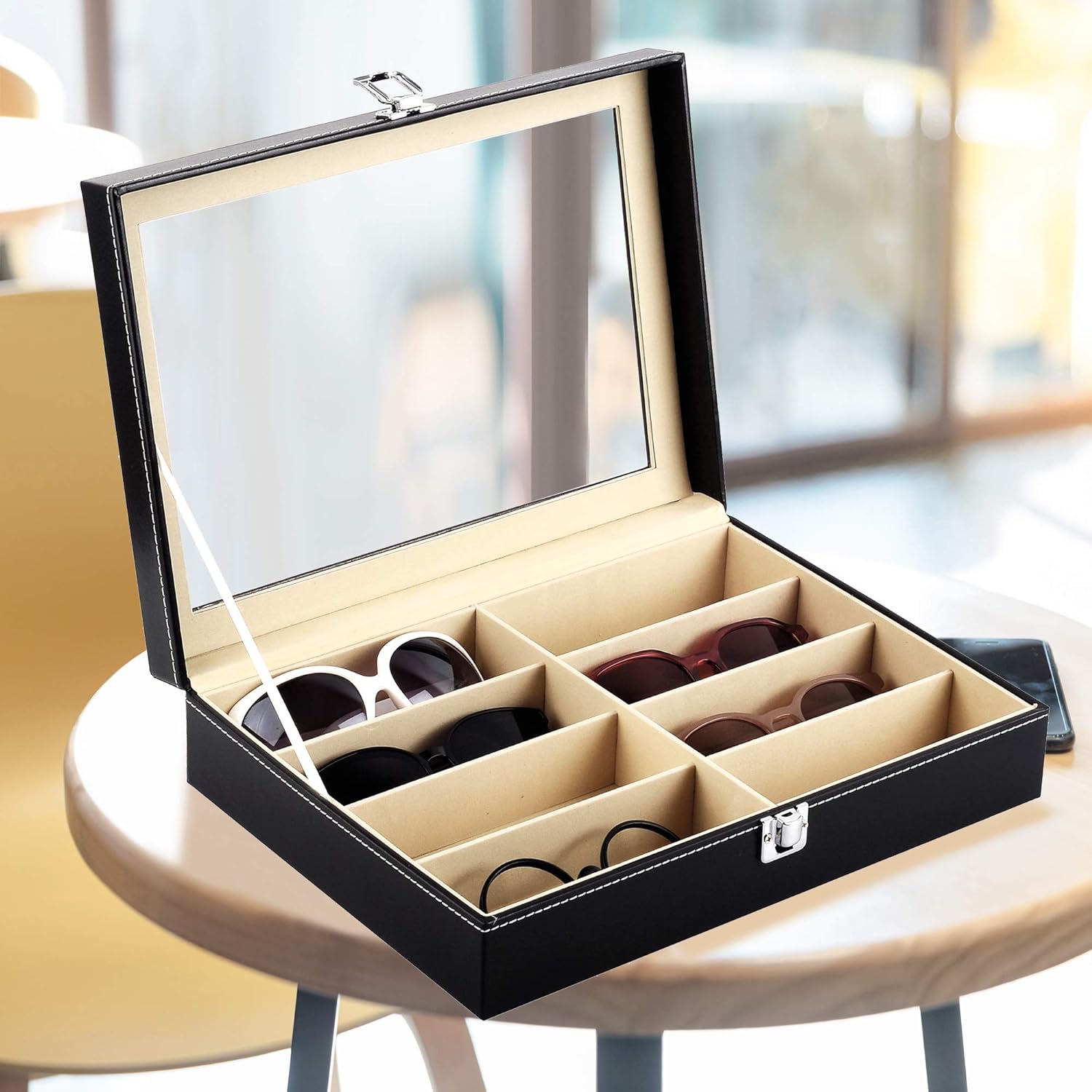 Black and beige eyewear display case with sunglasses on a table.