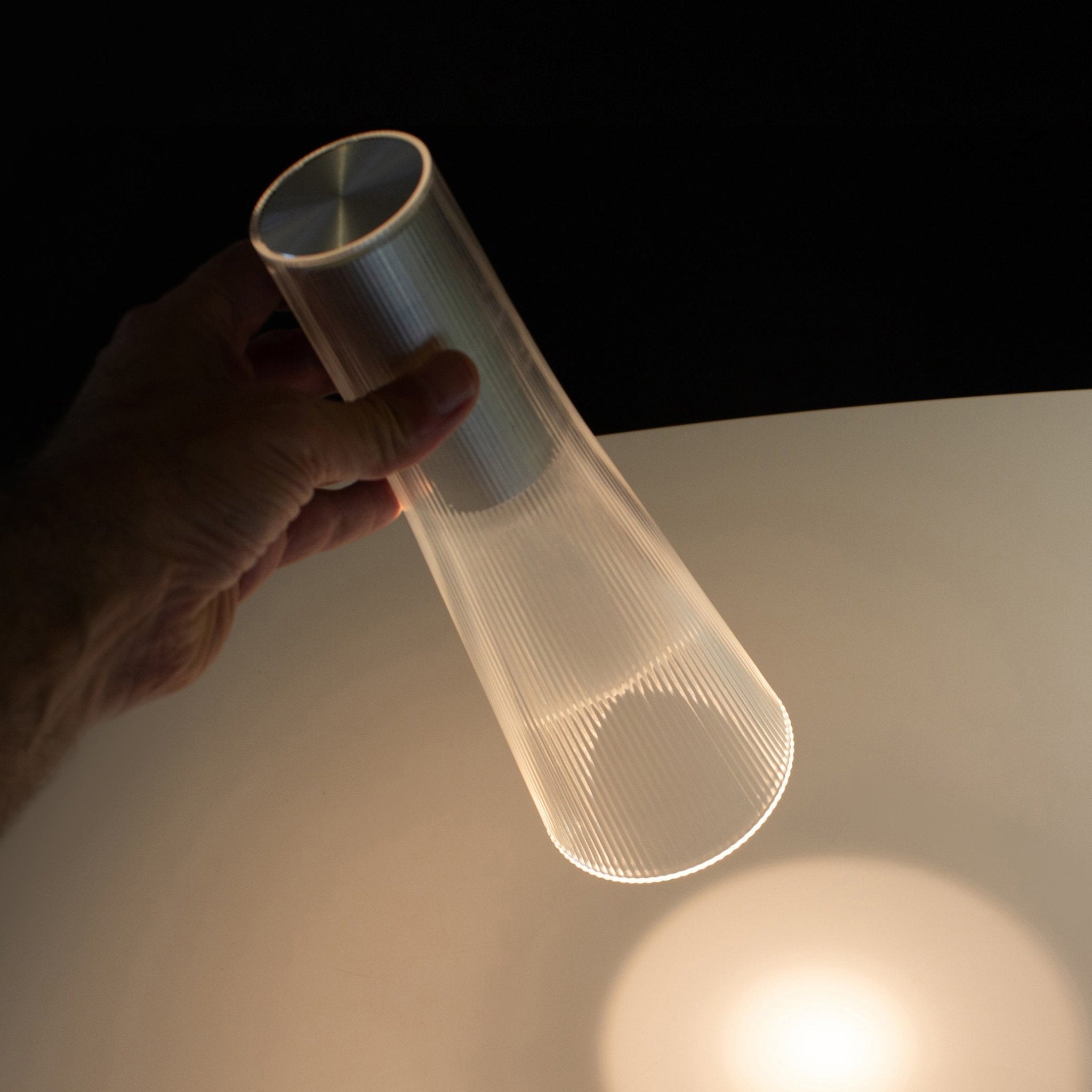 Hand holding a cylindrical light fixture against a dark background