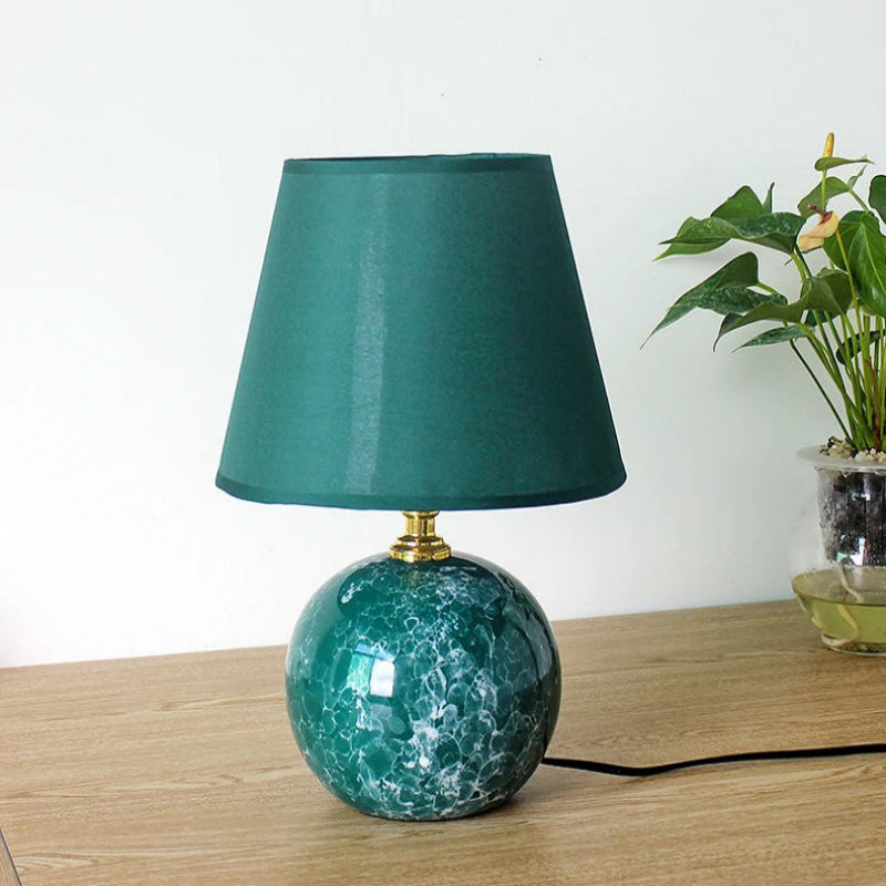 Teal table lamp with marble base on a wooden surface