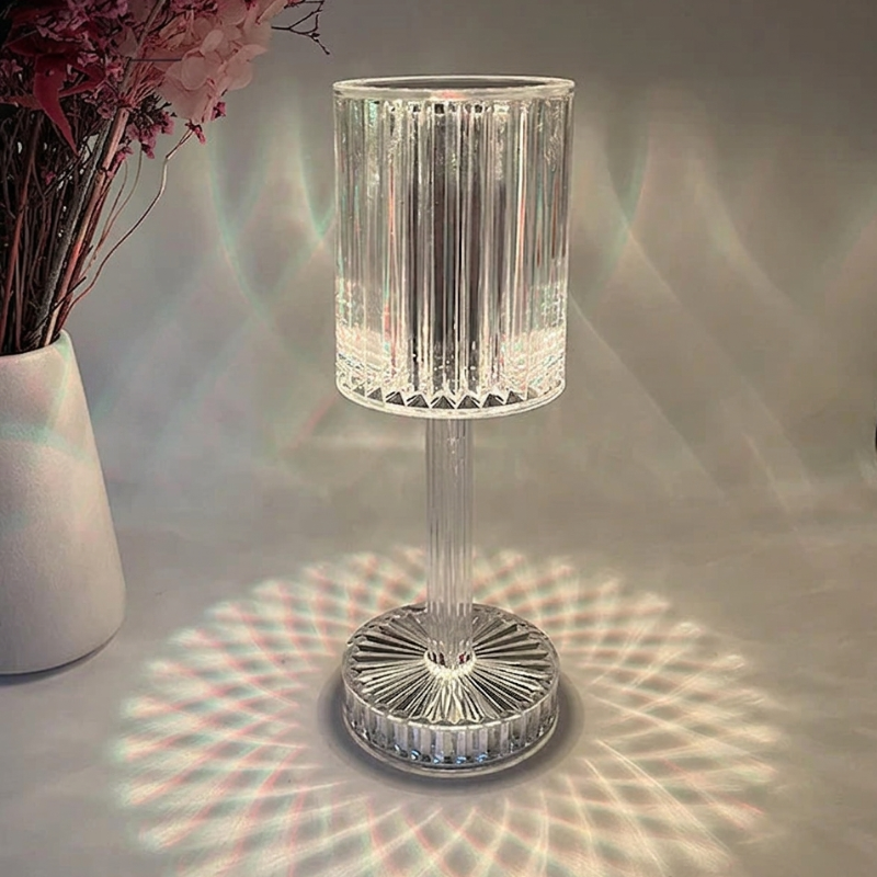 Crystal table lamp casting a pattern on a surface with a vase of flowers in the background.