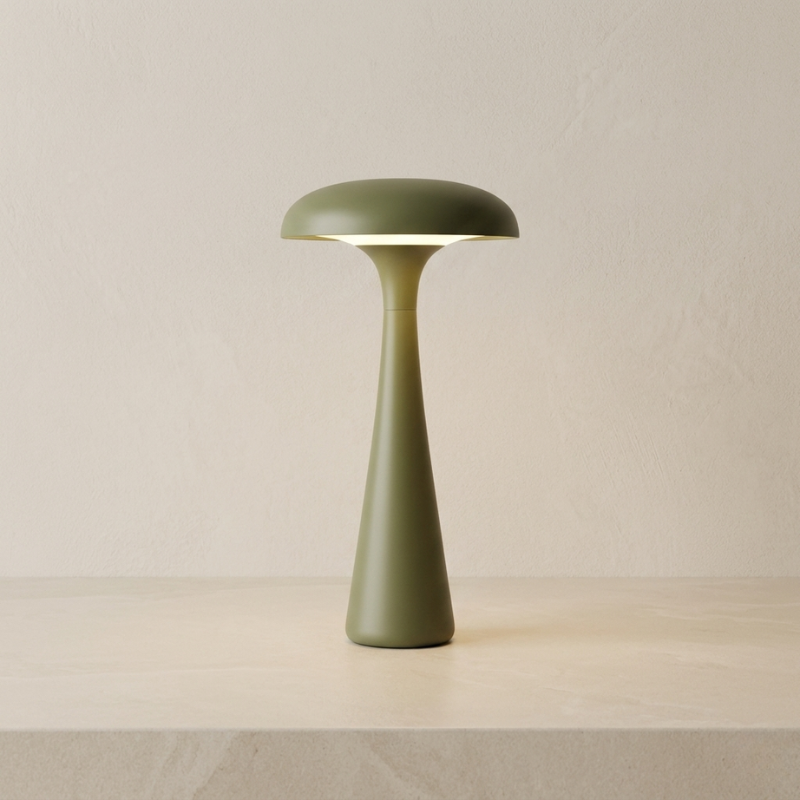 Green table lamp on a beige surface with a neutral background